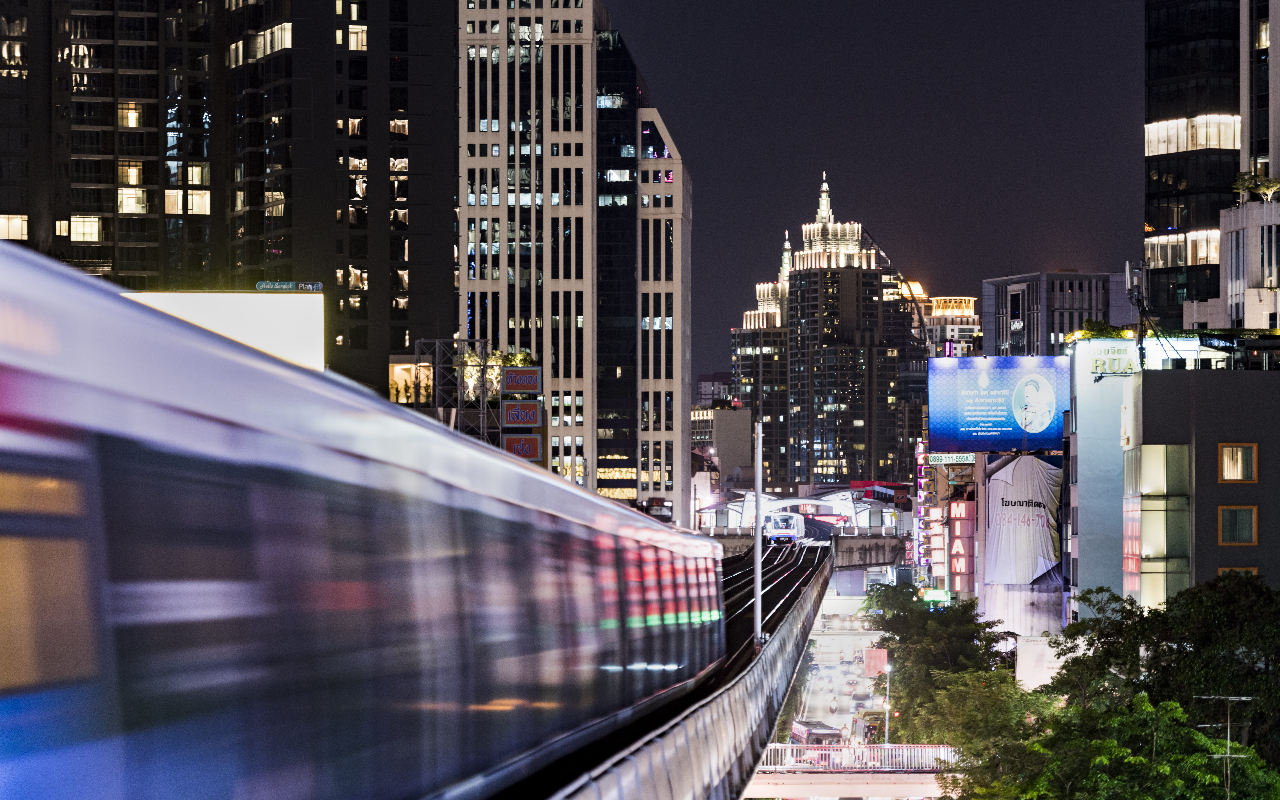 The BTS Skytrain running at night around buildings in Asoke, Bangkok.