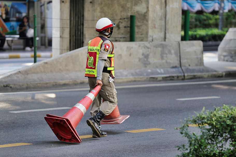 Police officer pulling traffic cones along a road in Bangkok