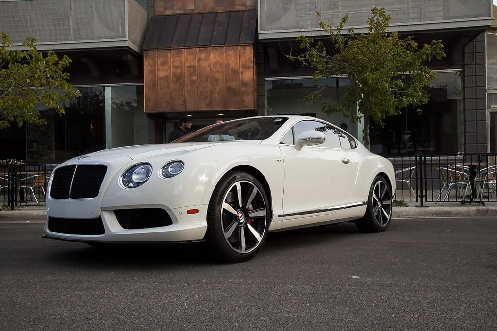 A white Bentley car parked in front of a building.