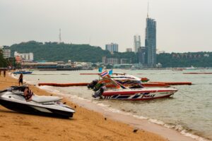A Boat near the City sign and the Waterfront Suites & Residences in Pattaya Beach.