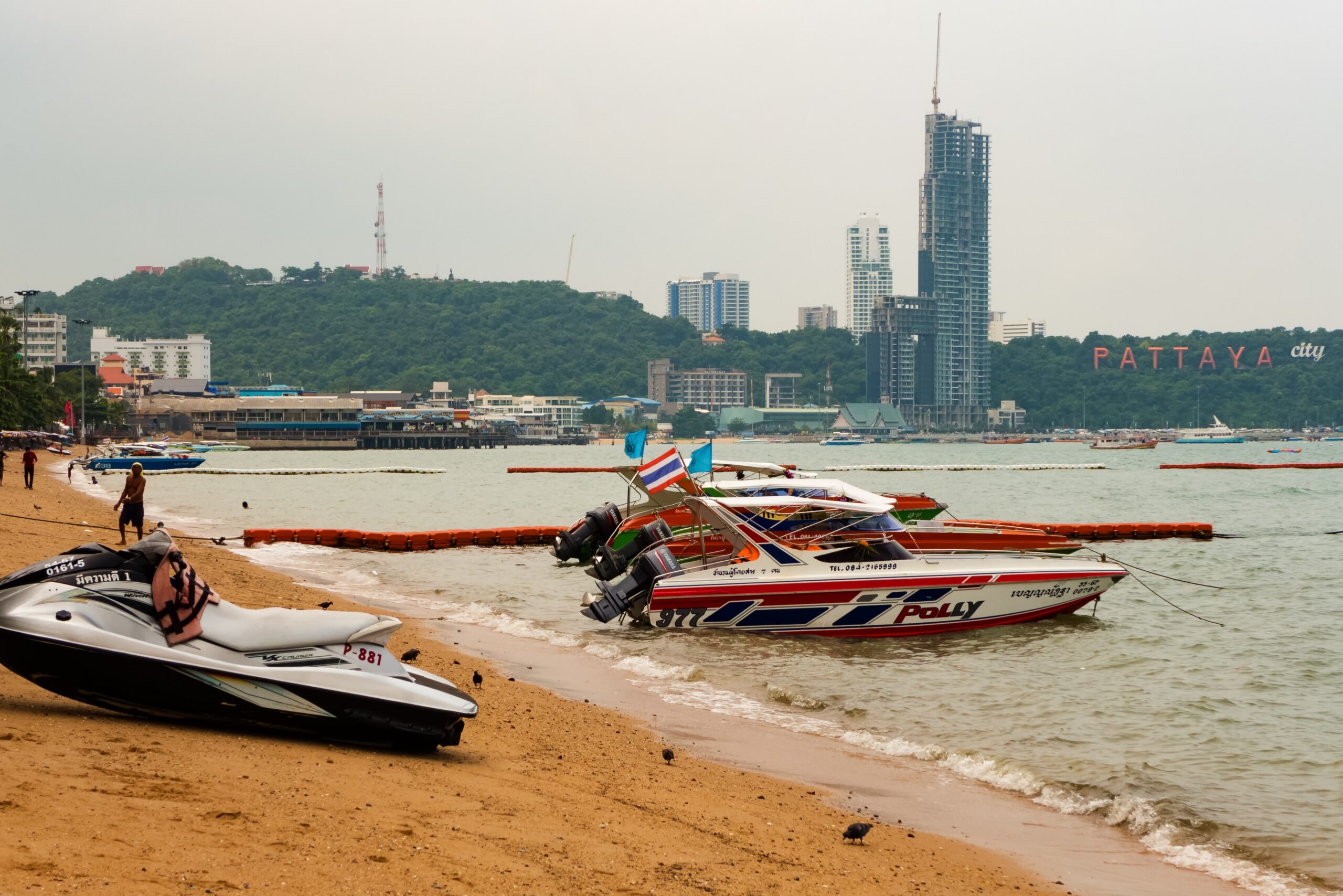 A Boat near the City sign and the Waterfront Suites & Residences in Pattaya Beach.