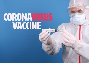 Doctor in face mask holding syringe with Coronavirus Vaccine text