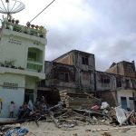 A small group of Indonesians stand near a building in a village where little remains after the earthquake and Tsunami that devastated the region of Sumatra, Indonesia