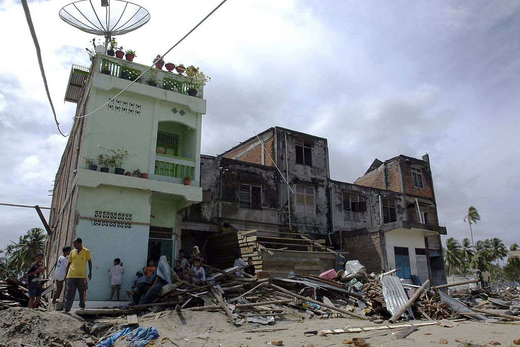 A small group of Indonesians stand near a building in a village where little remains after the earthquake and Tsunami that devastated the region of Sumatra, Indonesia