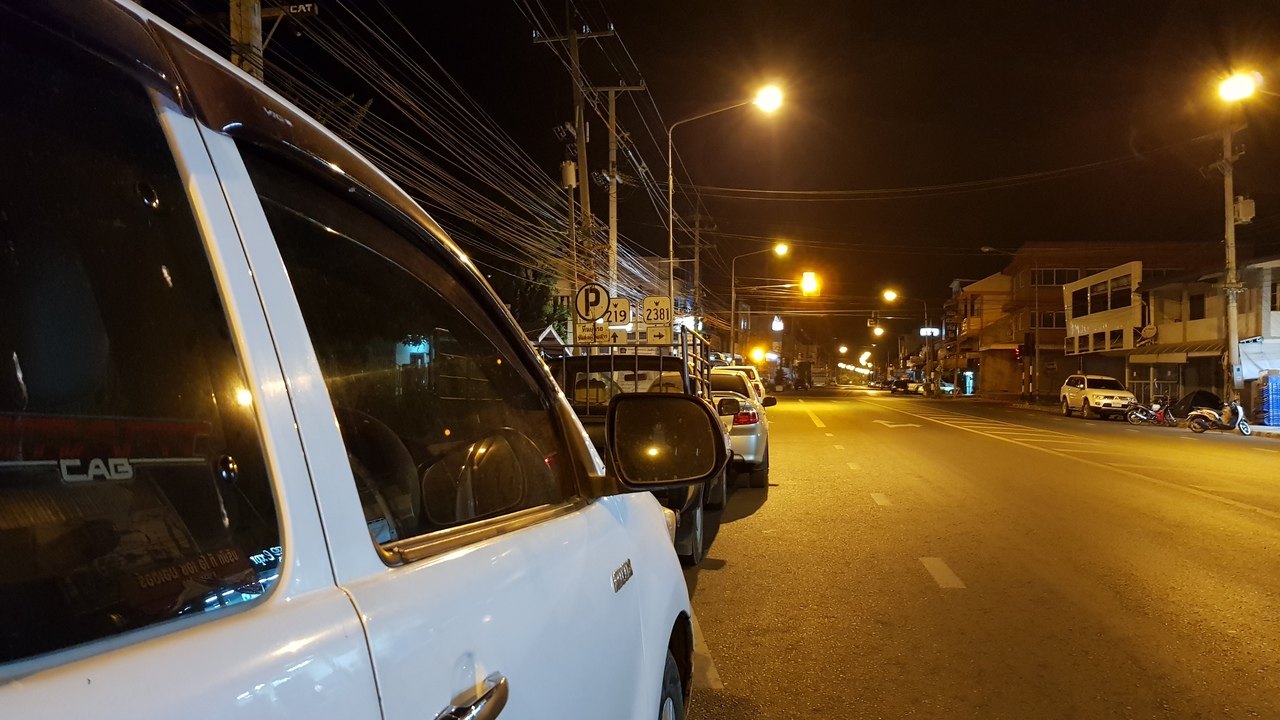 Pickup and cars parked in a empty street at night in Thailand.