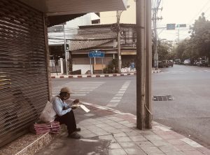 Man eating in a desert street in Bangkok in times of COVID-19 lockdown