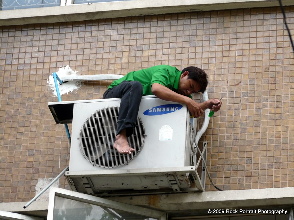 A man fixes an air conditioning unit in Bangkok.