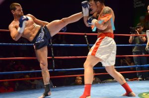 Muay Thai competitor attempts a high kick but it is blocked by his opponent