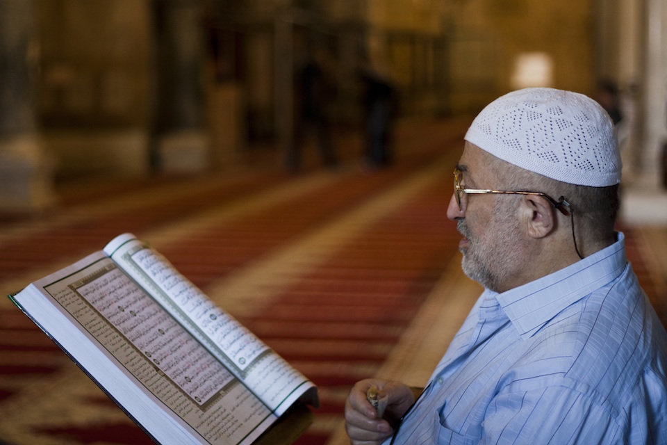 Muslim man reading the Quran in a mosqu
