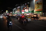 Cars and motorbikes driving on a Pattaya street at night.