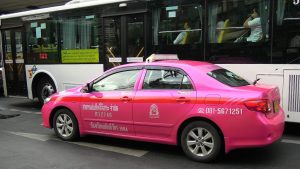 Colorful pink taxi and public bus in Bangkok