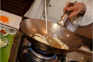 Jasmin rice being fried on a wok on a gas stove