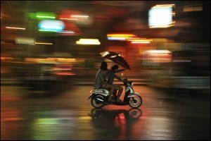 Couple with an umbrella riding a motorcycle in the rain