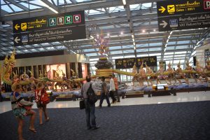 Inside the departures terminal at Suvarnabhumi International Airport in Bangkok. Gates and VAT Refund signs and the statue of the Hindu gods known as "stirring the ocean"