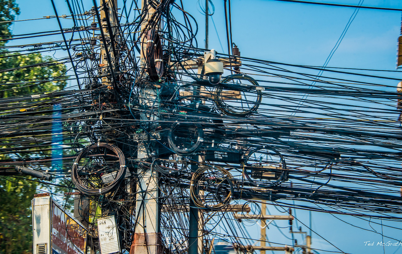 Typical tangled power cables on utility poles in Pattaya