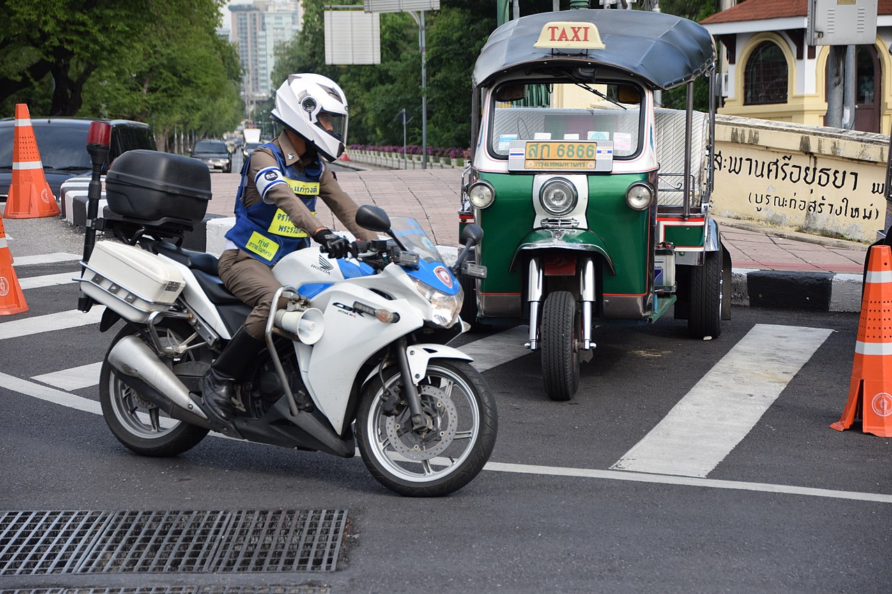 Thai police motorbike and a parked tuk tuk in Bangkok