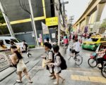 Thai people and passersby walking on Charoen Nakhon Street in Bangkok.