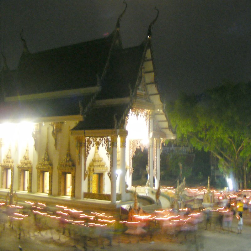 Walk with lighted candles in hand around a temple on Asalha Puja day