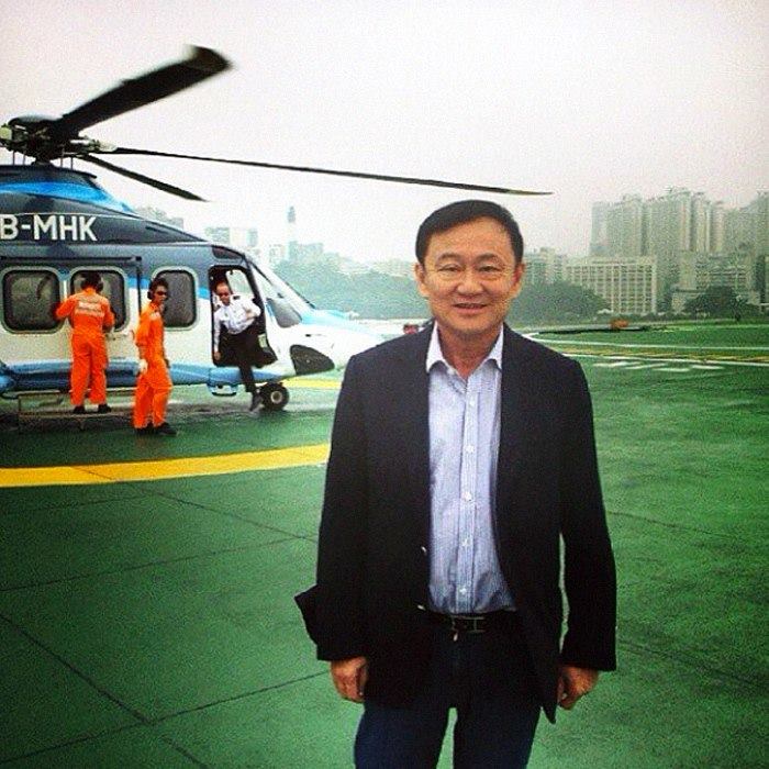 Thaksin Shinawatra posing near a helicopter.