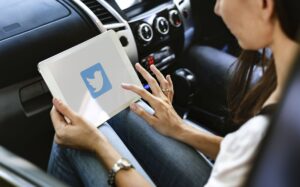 A woman using Twitter on a tablet in a car.