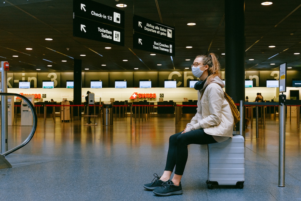 Woman wearing a mask waiting for her flight at the airport during the covid pandemic