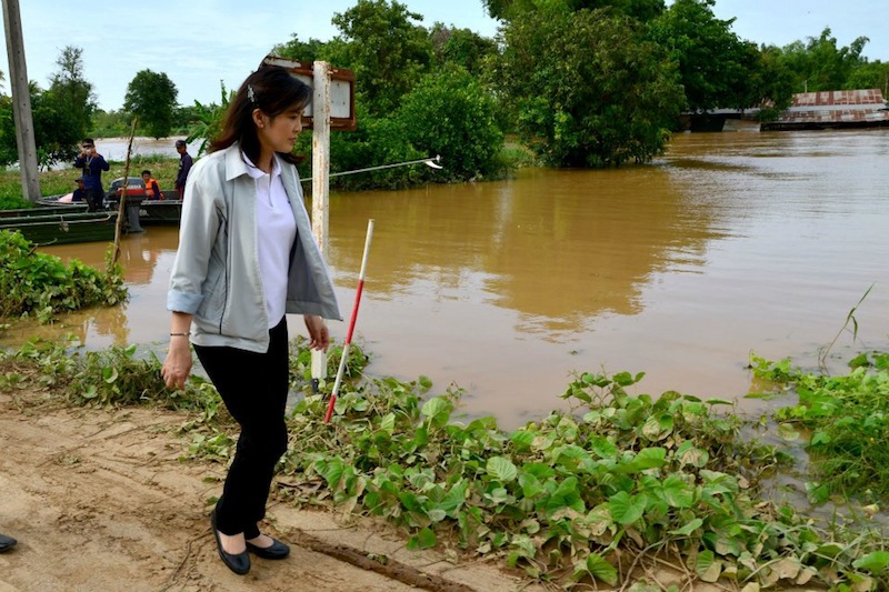 Yingluck Shinawatra walking near a pond