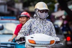 Girl wearing a face mask and sunglasses wearing a Honda scooter