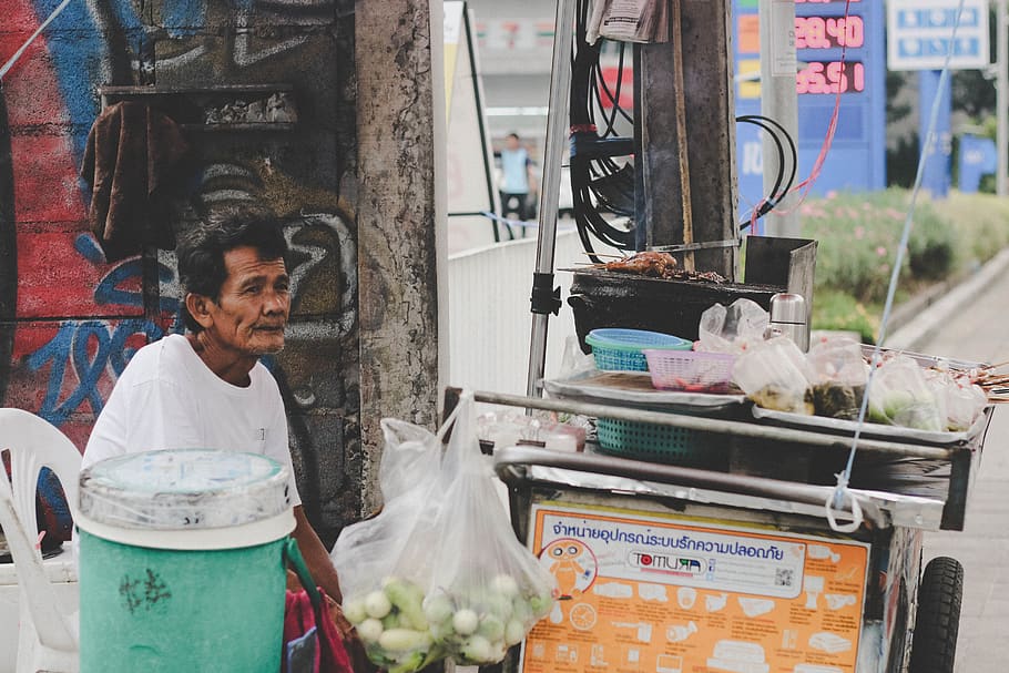 Food vendor sitting down behind a food stall