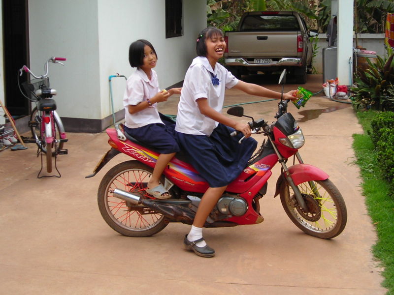 Young schoolgirls driving a motorcycle in Thailand